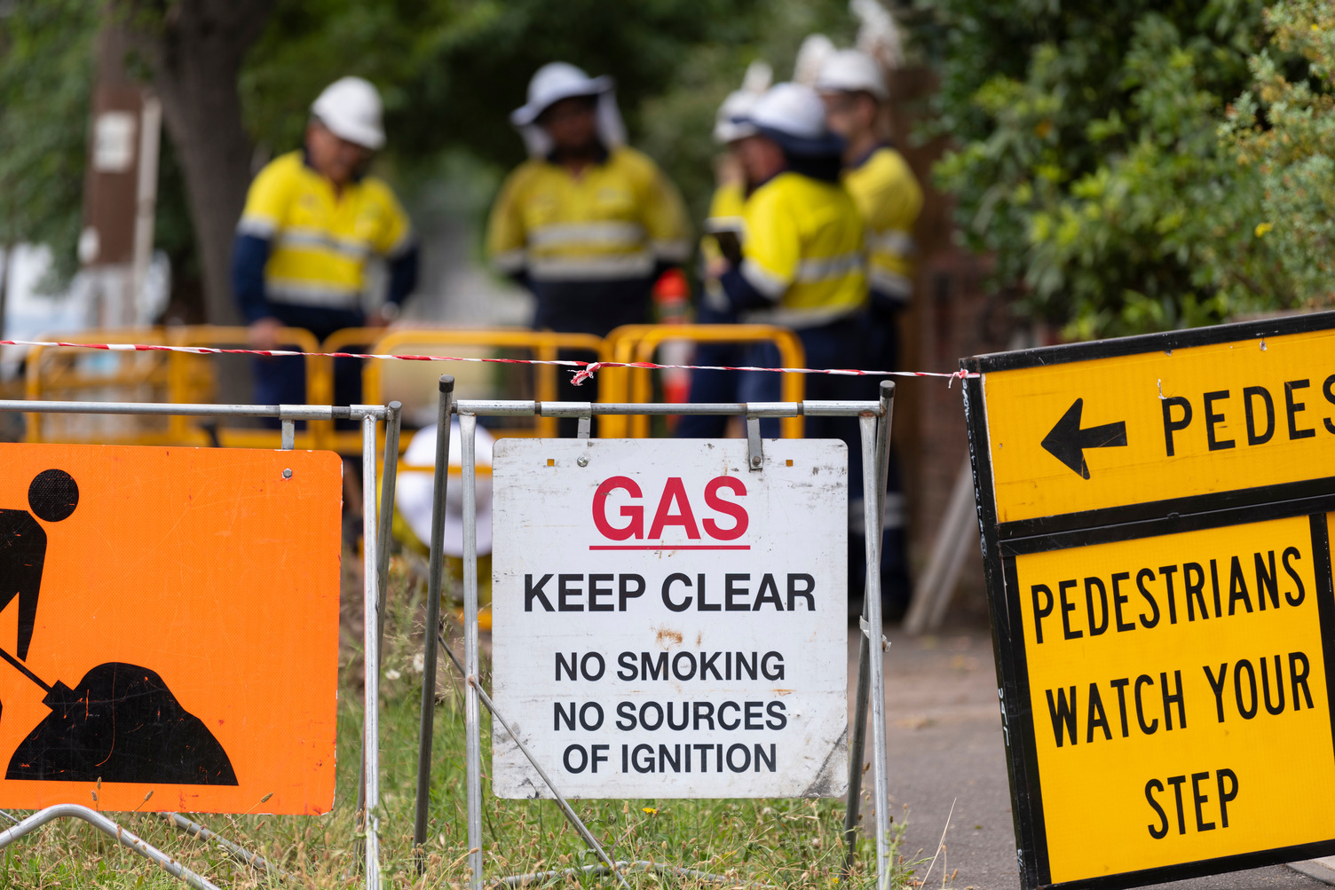 Various gas constructions signs on a street with workers in the background
