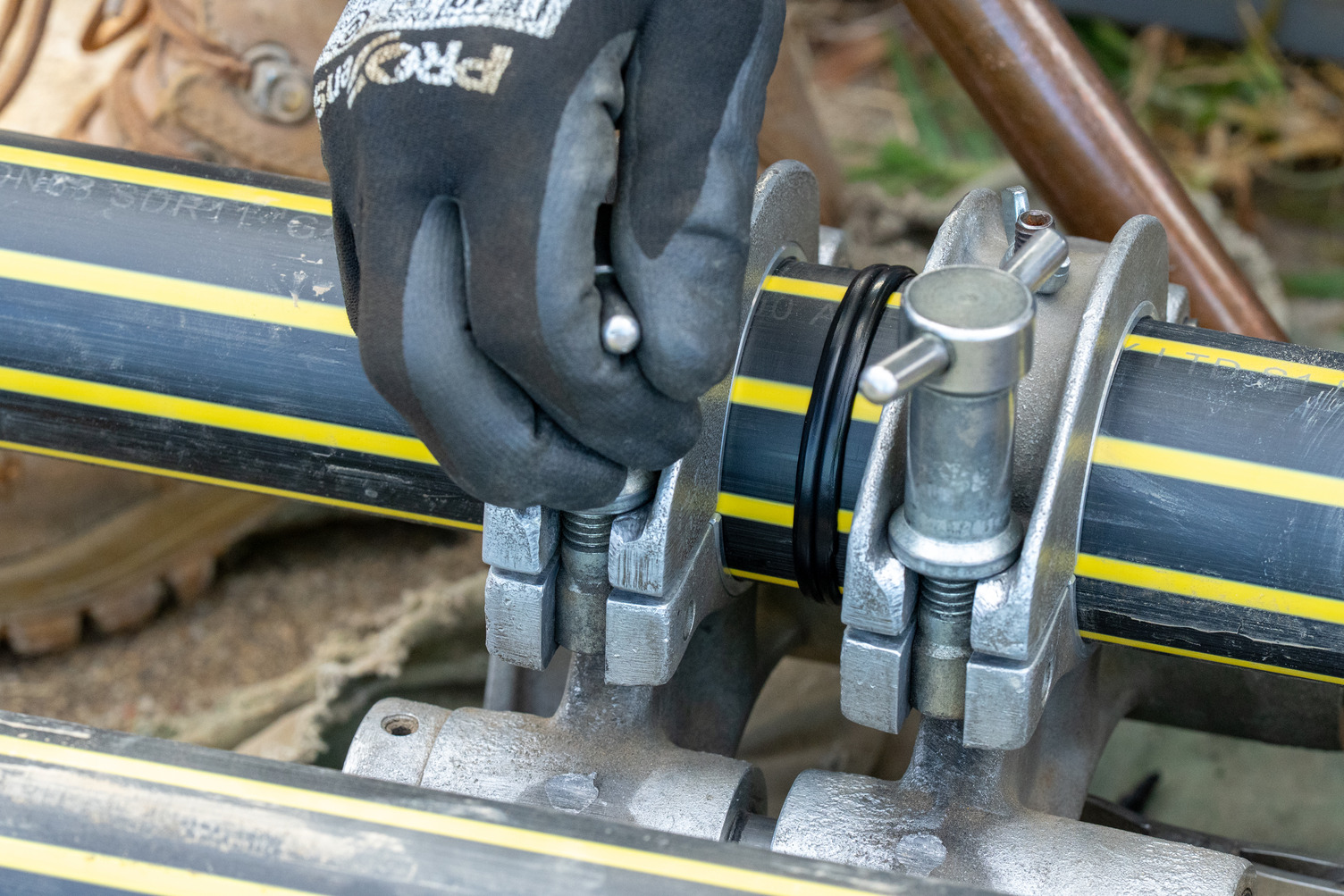 A gloved hand working on a gas pipe
