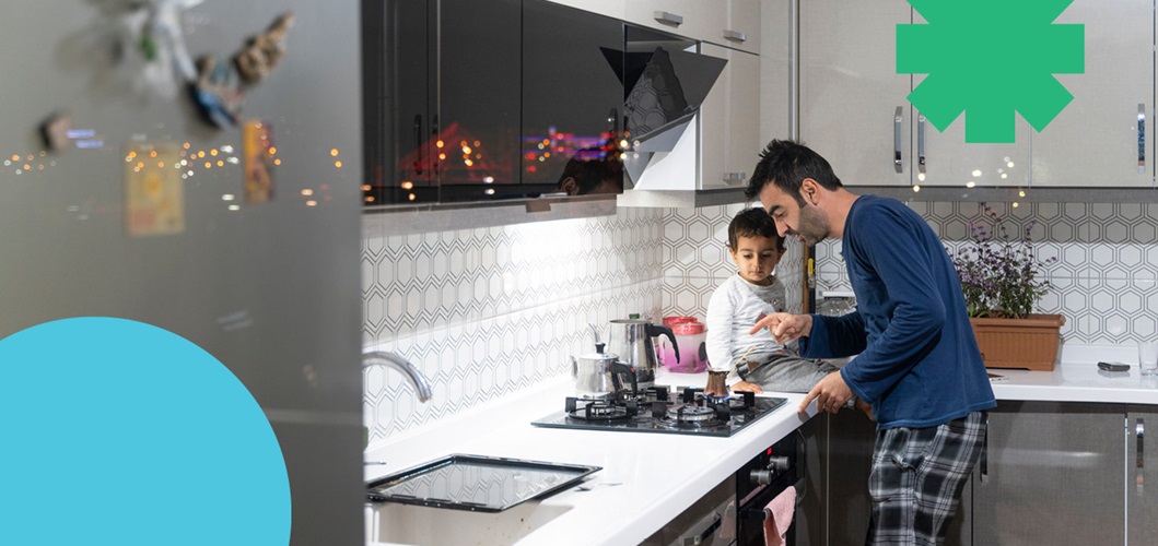 Father showing stove to son sitting on countertop 