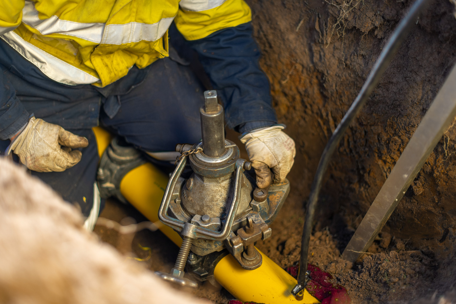 A contruction worker in a trench working on a gas pipeline