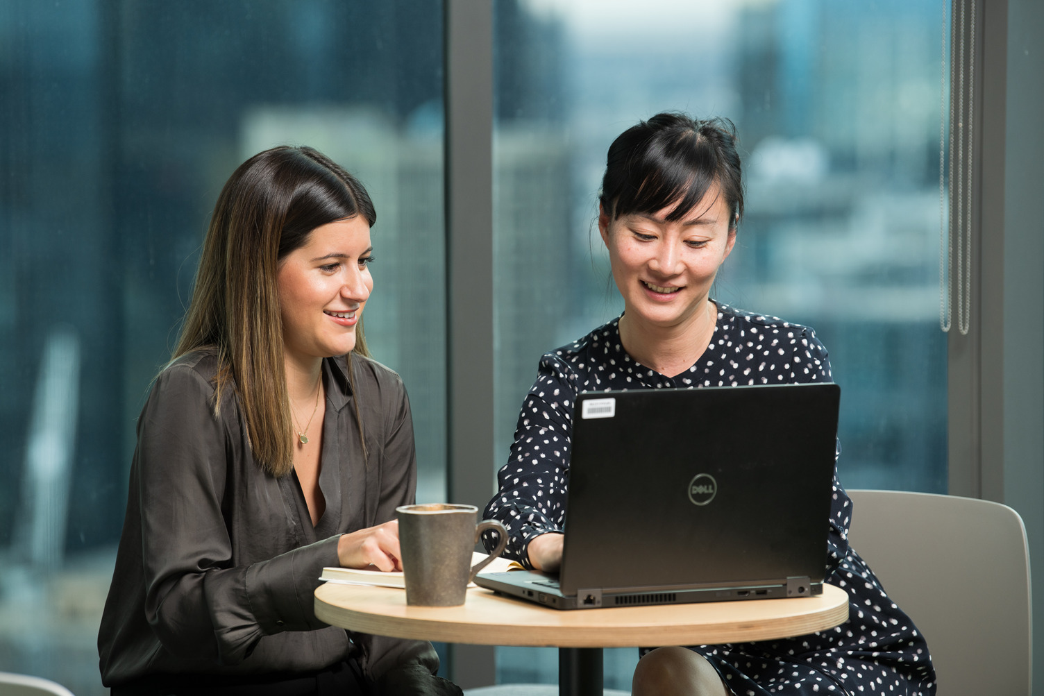 Two people smiling and looking at a laptop